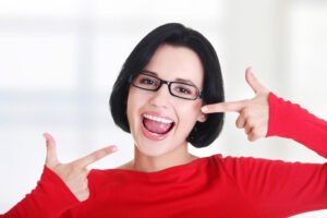 a woman pointing at her white smile after getting Teeth Whitening El Dorado Hills